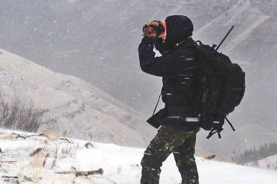 Hunter glassing for elk on a snowy ridgetop