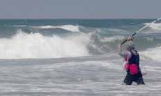 angler in the ocean surf casting for surfperch
