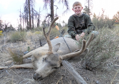 A young boy poses with a buck deer he shot with a bow and arrow