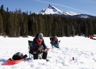 Two anglers ice fishing at Diamond Lake in the shadow of Mt. Thielsen
