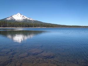 Fourmile Lake sprawls in the foreground with a snowy mountain in the background