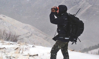 Hunter glassing for elk on a snowy ridgetop