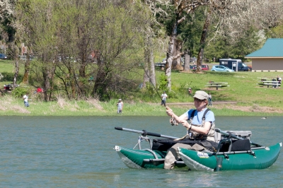 Angler on a pontoon boat making a cast with a fly rod