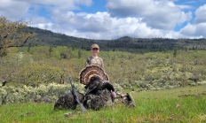 Young hunter standing with his turkey in an oak scrub landscape