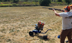 Shooter aiming a shotgun while instructor looks on