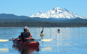 Kayaker photographing birds with mountain in background