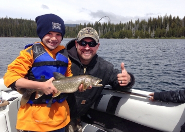 image of a father with a young son posing with a just-caught lake trout
