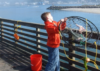 young crabbing chucking a crab pot off a pier