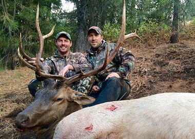 An elk hunter and friend posing with a trophy elk