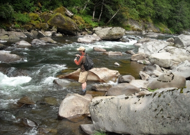 Steelhead angler fishing a rocky river bank