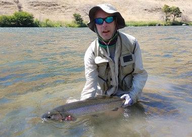 angler holding steelhead in water while he releases it