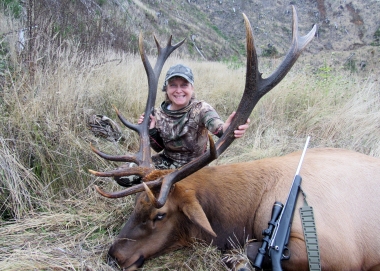 Young female rifle hunter poses with a big bull elk in the Stott Mt Unit.