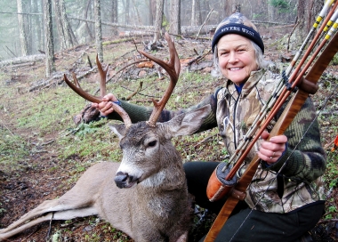 Female archery hunter with the black-tailed deer she shot with a traditional longbow.