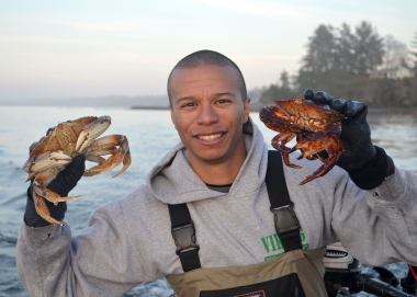 Smiling angler holds up a Dungeness crab in each hand