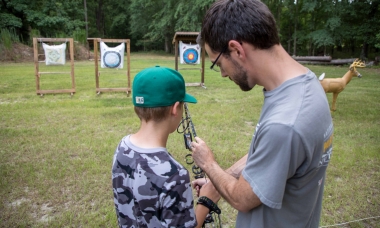 image of an archery instructor helping student with bow