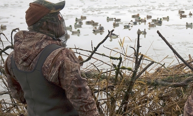 two hunters in a blind looking over decoys