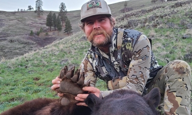 Spring hunter holds up the claw of a large, recently harvested bear.