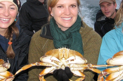 photo of three smiling women each holding a Dungeness crab