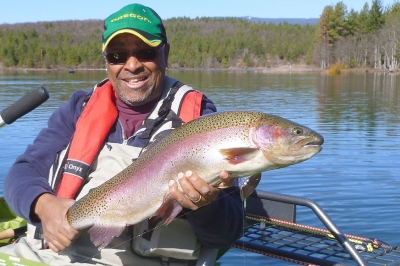 anglers holds a huge rainbow trout caught from pontoon boat