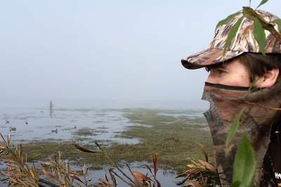 Camouflaged duck hunter scanning sky