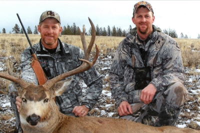 two hunters pose with a large harvested deer