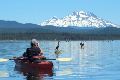 Kayaker photographing birds with mountain in background