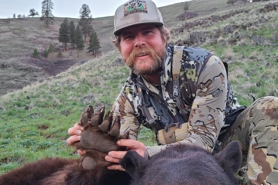 Spring hunter holds up the claw of a large, recently harvested bear.