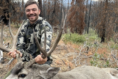 Hunter holds up the horns of a mule deer