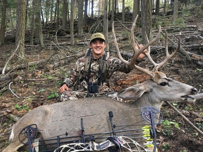 Parker poses with his archery bow and the mule deer he shot