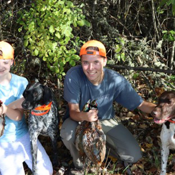Two young hunters with birds and dogs